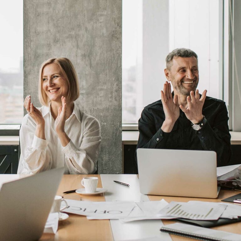 Two colleagues applauding in a meeting